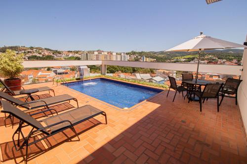 安帕鲁Prado Hotel的一个带游泳池、椅子和遮阳伞的庭院