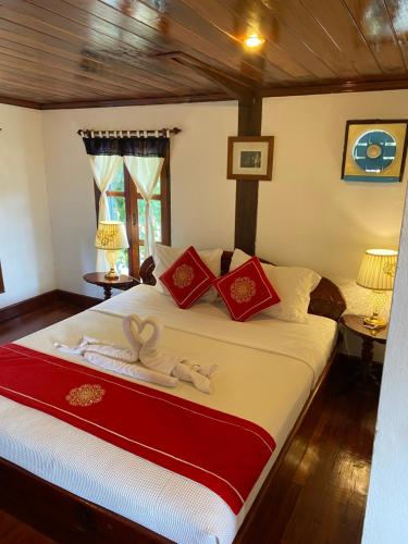 琅勃拉邦苏提考恩1号酒店的一间卧室配有一张带红色和白色枕头的大床