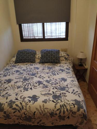 阿尔姆尼卡Casa baja cerca del mar的一张带蓝色和白色棉被的床和一个窗口
