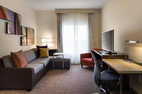 普莱诺Residence Inn by Marriott Dallas Plano/Richardson at Coit Rd.的一间客厅,客厅配有沙发和一张书桌,位于酒店的房间