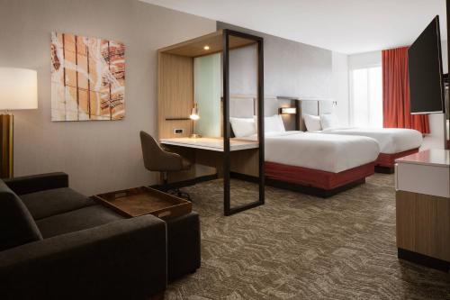 埃姆斯SpringHill Suites by Marriott Ames的酒店客房设有两张床、一张桌子和一张沙发。