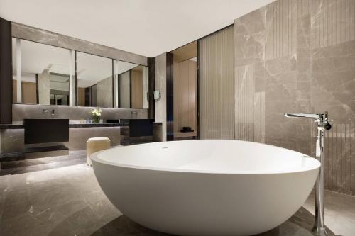 宝安深圳同泰万怡酒店的浴室设有大型白色浴缸,配有镜子