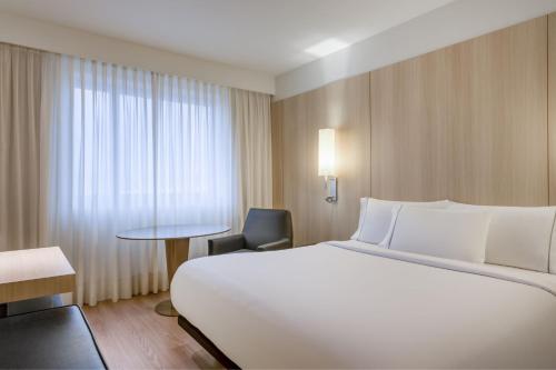 科尔多瓦AC Hotel Córdoba by Marriott的酒店客房设有一张白色大床和椅子