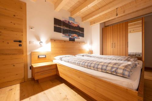 维哥迪法萨Ciasa Marta的一间卧室配有一张带木墙的大床