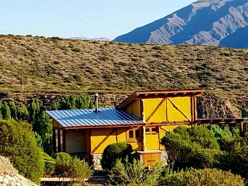 波特雷里约斯Cabaña La Mostacita - Complejo El Taller的山上一座黄色房子,屋顶蓝色