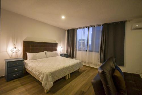 瓜达拉哈拉Expo Satelite Hotel & Suites的卧室配有床、椅子和窗户。