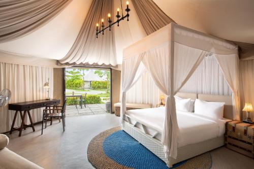 拉古洼Natra Bintan, a Tribute Portfolio Resort的一间卧室配有一张天蓬床和一张书桌