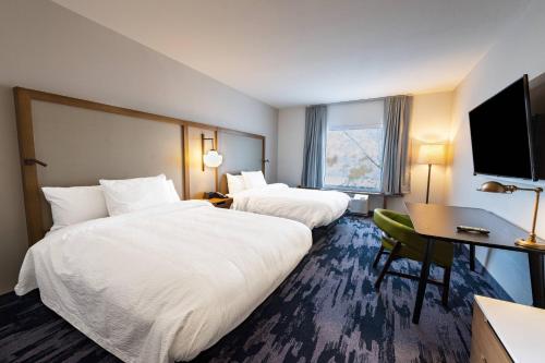 凤凰城Fairfield Inn & Suites by Marriott Phoenix West/Tolleson的酒店客房设有两张床、一张桌子和一台电视。