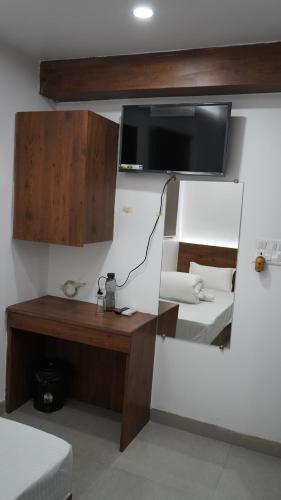 贾姆谢德布尔POD N BEYOND SMART HOTEL @BISTUPUR的客房设有书桌和墙上的电视