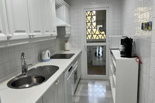 锡蒂奥卡拉翁达MI CAPRICHO 4C BEACHFRONT -Apartment with sea view - Costa del Sol的厨房配有白色橱柜、水槽和门