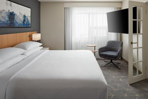 卡尔加里Delta Hotels Calgary Airport In-Terminal的卧室配有一张白色大床和一把椅子
