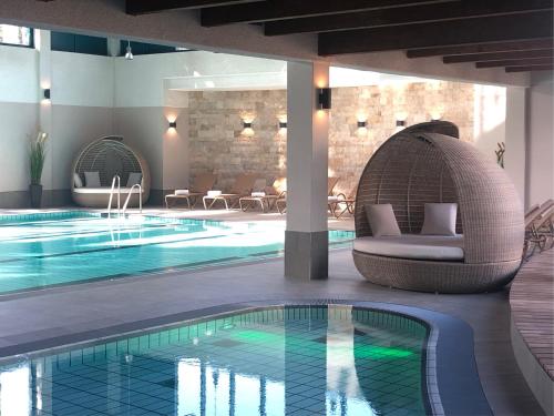 朱列斯拉赫阿克马里斯斯特兰得利斯等吕根酒店 的一座游泳池,旁边是一座建筑,配有藤椅