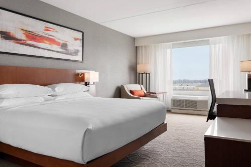 印第安纳波利斯Delta Hotels by Marriott - Indianapolis Airport的酒店客房设有一张白色大床和一个窗户。