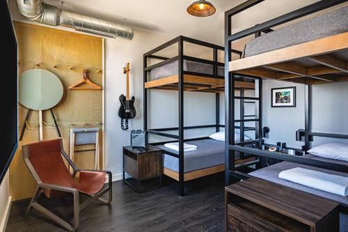 明尼阿波利斯明尼阿波利斯上城区慕奇夕酒店的客房设有双层床、书桌和椅子。