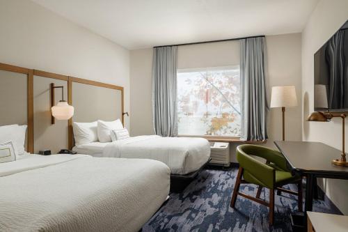 萨利纳Fairfield Inn & Suites by Marriott Salina的酒店客房设有两张床、一张书桌和一个窗户。