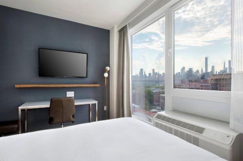 皇后区TownePlace Suites by Marriott New York Long Island City的卧室设有大窗户,享有城市美景。