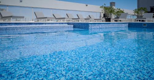 罗萨里奥广场里尔套房酒店的一座大型蓝色游泳池,里面配有椅子