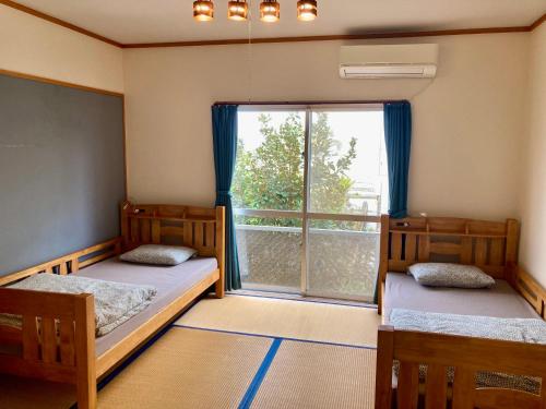 读谷村人生旅程旅馆的带大窗户的客房内的两张床