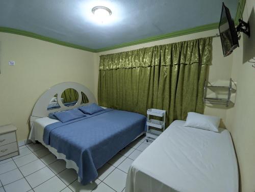马那瓜Hotel Fuente de Paz Managua的一间卧室配有两张床和镜子