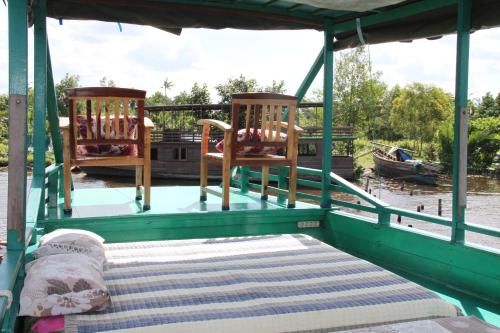 庞卡兰布翁Orangutan Kelotok Houseboat for 6 person的两把椅子和一张船后床