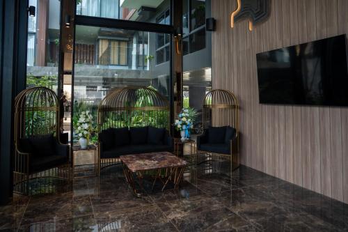 Ban KohongRichmann Resort Hotel Hatyai的大堂设有两只鸟笼、椅子和桌子