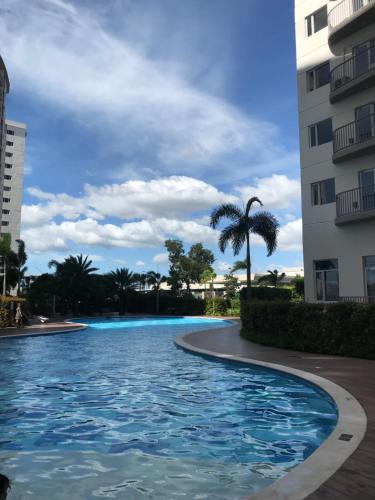 马尼拉South Residences staycation的棕榈树建筑前的游泳池