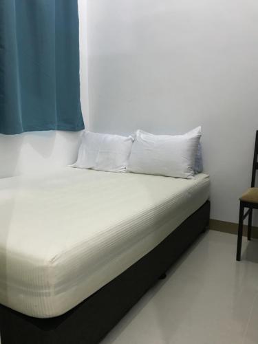 马尼拉South Residences staycation的一张带白色床单和枕头的床