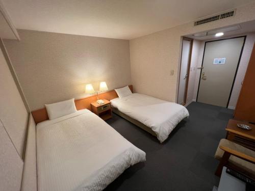 北见Kitami Daiichi Hotel - Vacation STAY 73148v的酒店客房设有两张床和两盏灯。