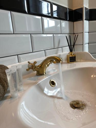 米德尔克尔克Villa La Dune - Ontbijt & parking inclusief的浴室内白色水槽和金色水龙头