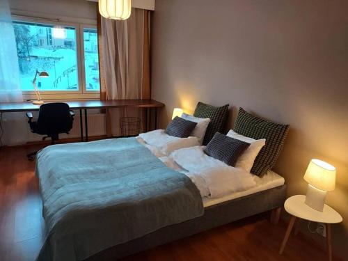 赫尔辛基Cosy two rooms apartment in Helsinki的一间卧室配有一张带枕头的床和一张书桌