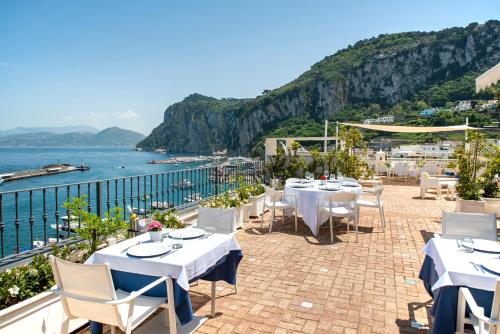 卡普里Relais Maresca Luxury Small Hotel & Terrace Restaurant的餐厅设有桌椅,俯瞰着大海