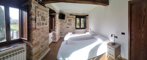 SerantesCasa Bagaro的一间设有两张白色床铺和砖墙的房间