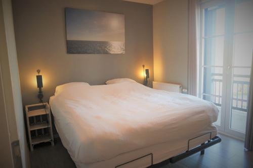卡德赞德-班得Caramia, Duinhof, Romantic apartment by the sea的卧室设有一张白色大床和一扇窗户。