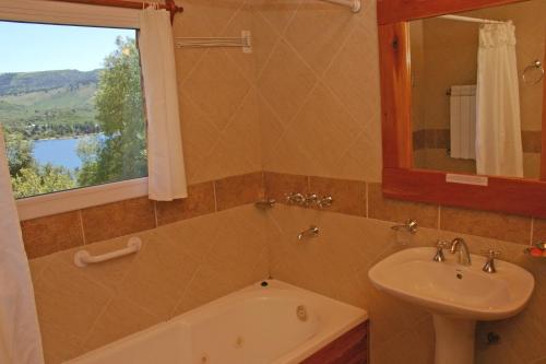 佩休尼亚镇帕拉伊索宾馆的一间带水槽和浴缸的浴室以及窗户。
