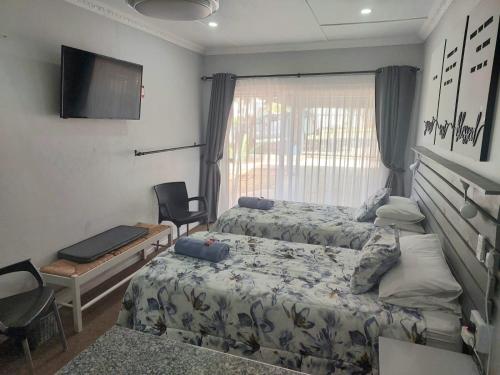 阿仕顿Rest4Sure的一间卧室配有两张床、一张桌子和一台电视。