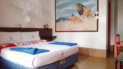 Sultan HamudMiryams Village Inn Safari Lodge的卧室配有一张床,还展示了狮子的照片