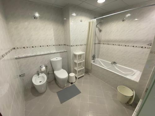 迪拜One bedroom apartment with pool & gym near Marina的浴室配有卫生间、浴缸和水槽。