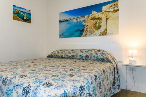 圣凯撒利亚温泉Camping La Scogliera的卧室配有一张床,墙上挂有绘画作品