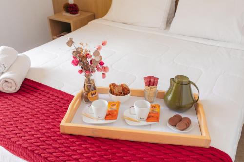 蒂拉登特斯Pousada Relicário的床上的托盘,上面装有咖啡杯和糕点