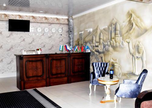 撒马尔罕Osiyo Hotel的一间设有两把椅子、一张桌子和一面墙的房间