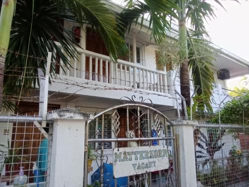 DaanbantayanMatterhorn Guest House的一座白色的房子,有门和棕榈树