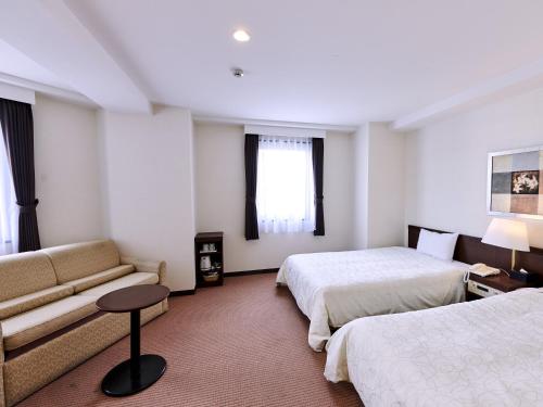 长野Hotel Courtland的酒店客房,设有两张床和一张沙发