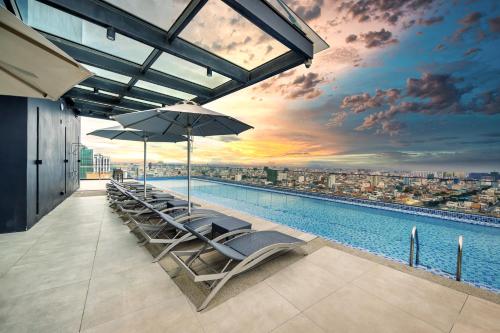 金边Luxcity Hotel & Apartment的一座带椅子和遮阳伞的游泳池