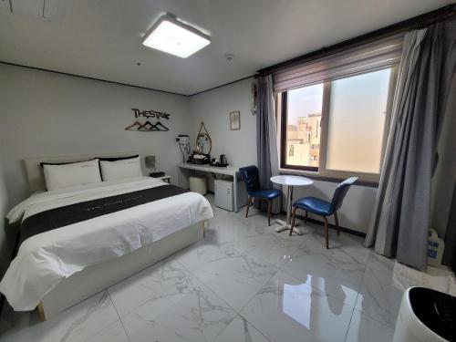 丽水市Yeosu Thestay Hostel的酒店客房带一张床、一张桌子和椅子