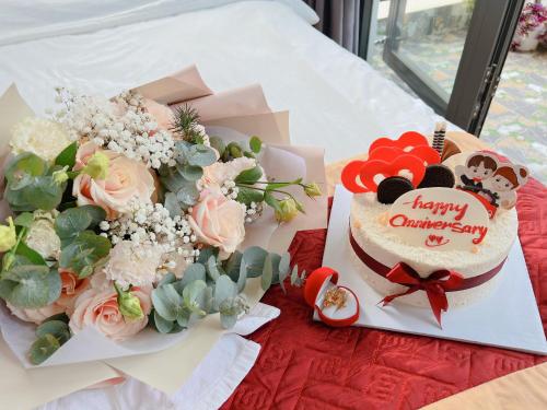 大叻Ánh Vân Villa hotel的桌上的生日蛋糕和鲜花