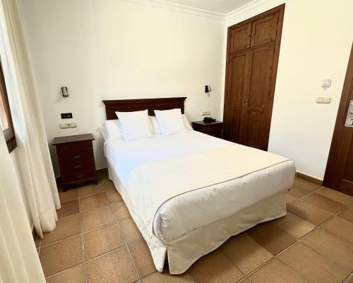 萨阿拉德洛斯阿图内斯Hostal La Muralla的卧室配有一张带白色床单和枕头的大床。