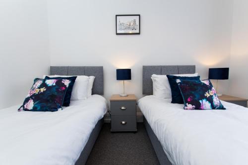 ArkseyK Suites - Ely Road的两张睡床彼此相邻,位于一个房间里