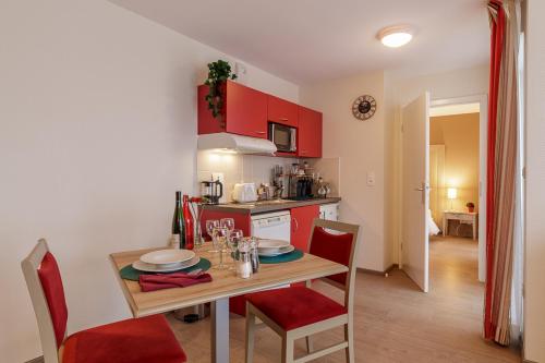 斯特拉斯堡Zenao Appart'hôtels Strasbourg的厨房配有红色橱柜和桌椅