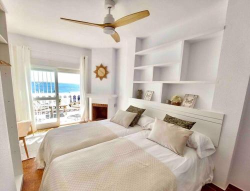 托雷德尔马尔Caleta Beach House Villa Beatriz Sinese Design的白色卧室配有两张床和吊扇