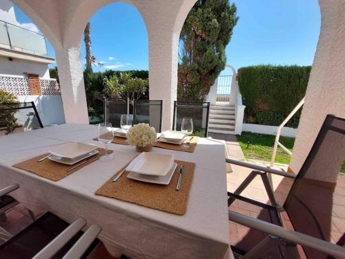 托雷德尔马尔Caleta Beach House Villa Beatriz Sinese Design的庭院上配有带盘子和玻璃杯的白色桌子